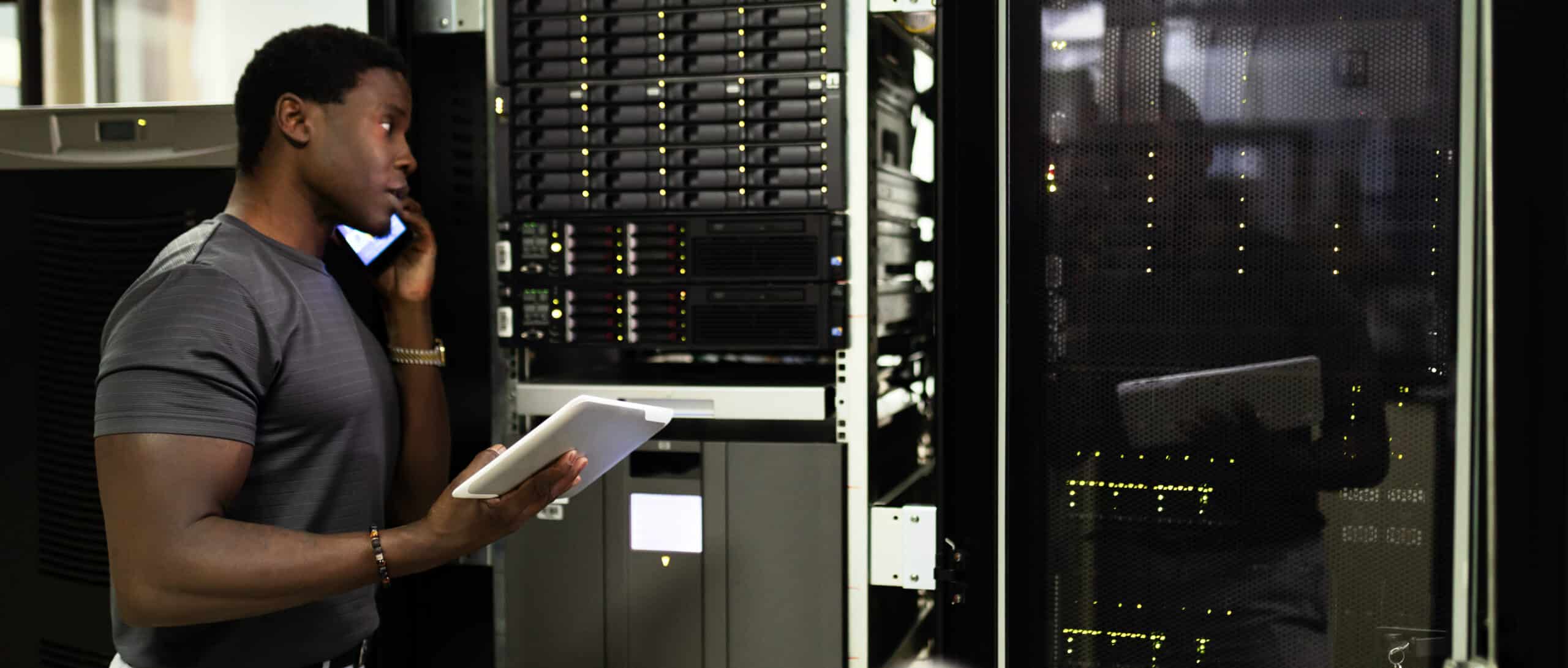 Black person is working in data center with laptop