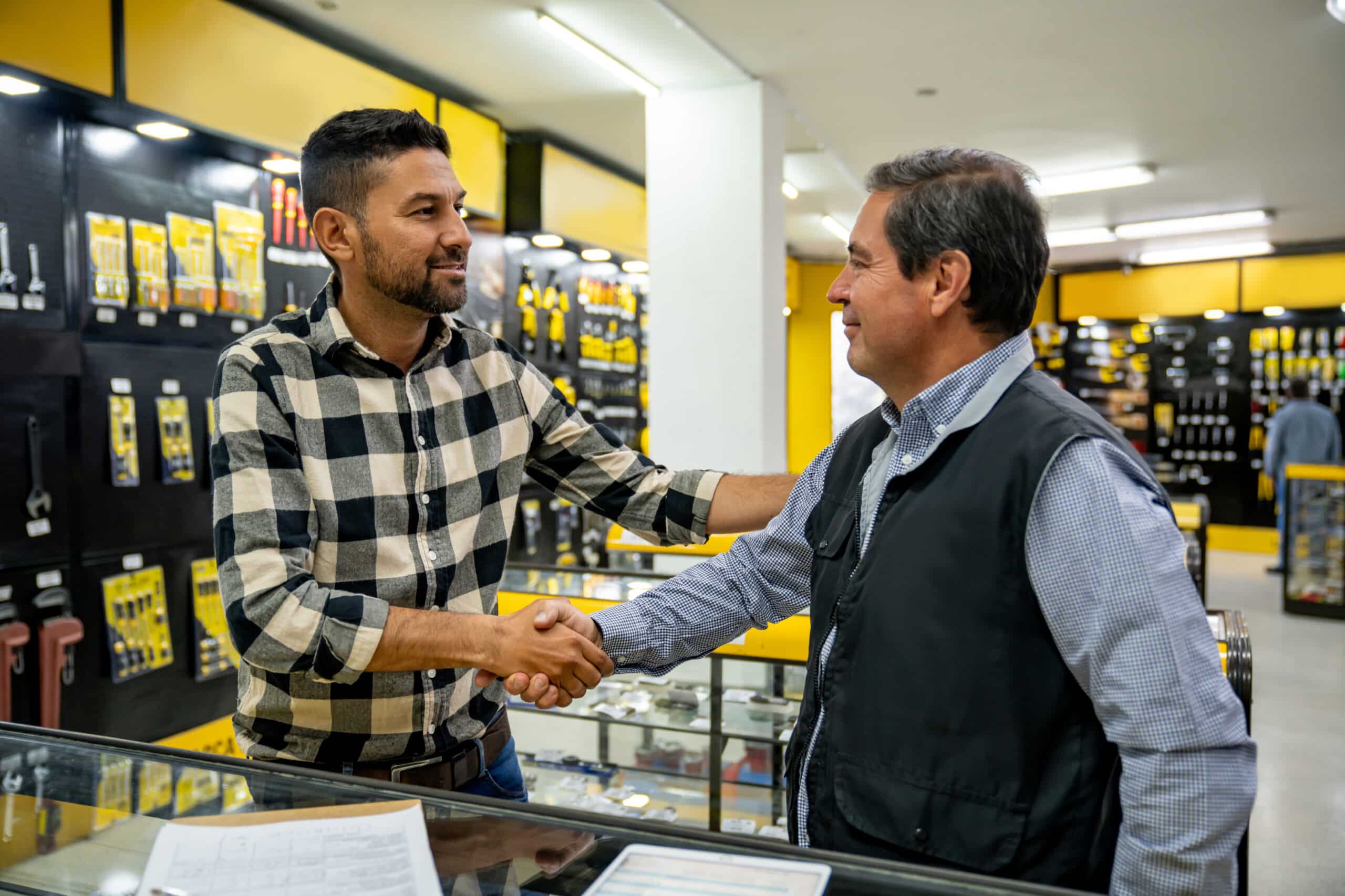 Latin American customer handshaking the retail clerk that help him while buying tools at the hardware store